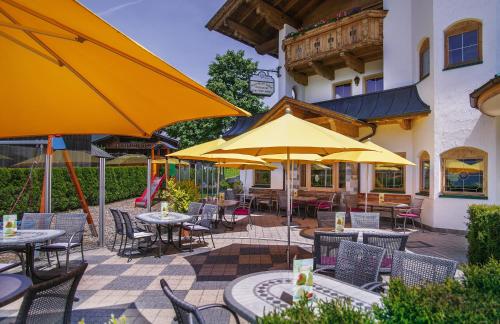 an outdoor patio with tables and chairs and umbrellas at Apparthotel Talhof, Restaurant, Pool und Spa in Oberau