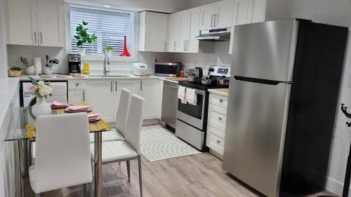 cocina con nevera y mesa con sillas en Modern, self-contained 2b/ 1.5 b suite w/workspace, en Distrito municipal de Maple Ridge