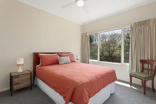 a bedroom with a bed and a chair and a window at Curragundi in Point Lonsdale