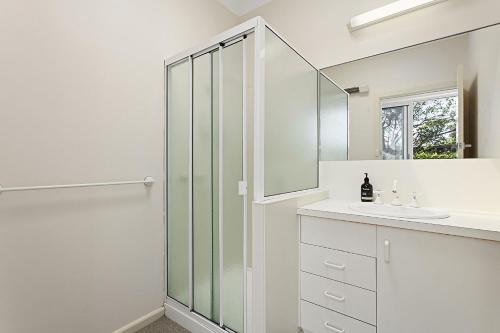 ein weißes Bad mit einer Dusche und einem Waschbecken in der Unterkunft Curragundi in Point Lonsdale