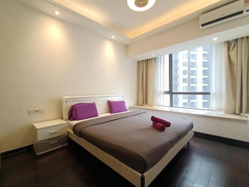 um quarto com uma cama com almofadas roxas e uma janela em R&F Princess cove Sweety Homestay 3beds2baths em Johor Bahru