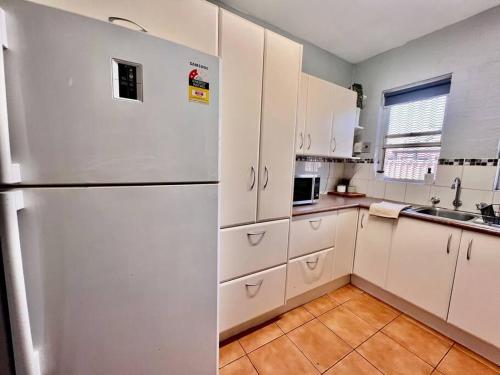 cocina con armarios blancos y nevera en Renovated 2 Bedroom - Managers Apartment en South Hedland