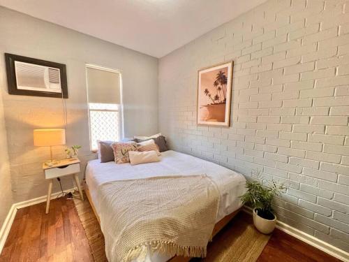 um quarto com uma cama e uma parede de tijolos brancos em Renovated 2 Bedroom - Managers Apartment em South Hedland