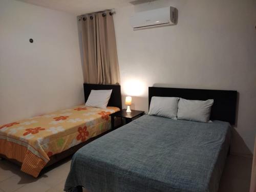 a bedroom with two beds and a lamp on a table at HOSPEDAJE MAGNOLIAS MERIDA in Mérida