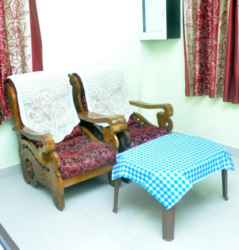 Revathy Tourist Home في Kallar-Bridge: كرسيين وطاولة في الغرفة