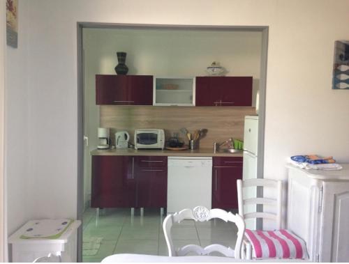 une cuisine avec des placards violets et des appareils blancs dans l'établissement Maison en plein cœur de la tranche sur mer 500 m plage, à La Tranche-sur-Mer