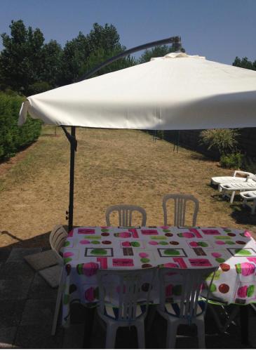 - une table avec un parasol et des chaises blancs dans l'établissement Maison en plein cœur de la tranche sur mer 500 m plage, à La Tranche-sur-Mer