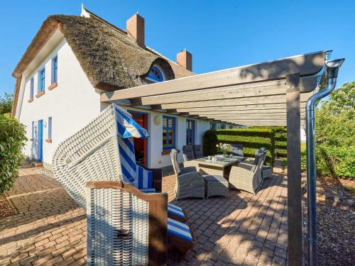 a house with a thatched roof and a patio at Reethaus Zickersche Berge - WG 02 mit Kamin und Terrasse in Gager