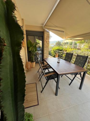 einen Holztisch und Stühle auf einer Terrasse in der Unterkunft Pool apartment 5 minutes walk from beach in Porto Rafti
