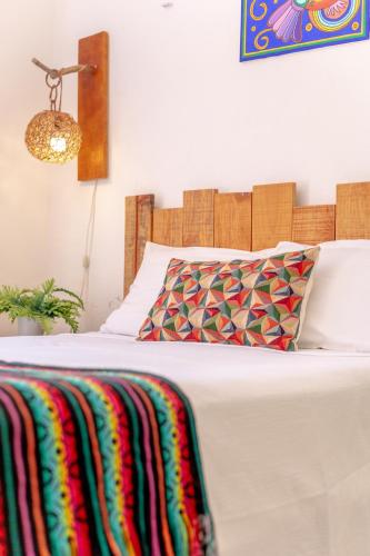 a white bed with a colorful blanket on it at In Wotoch Departamentos con Estacionamiento in Valladolid