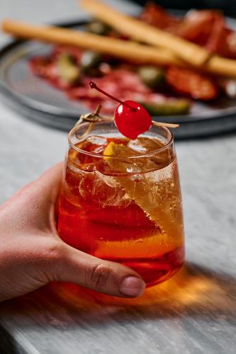 a hand holding a drink with a cherry on top at Rydges Geelong in Geelong