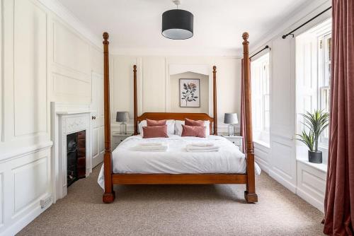 um quarto com uma cama de dossel e almofadas cor-de-rosa em Stunning 3 Bedroom Period City Centre Apartment em Bath