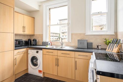 a kitchen with a sink and a washing machine at Stunning 3 Bedroom Period City Centre Apartment in Bath