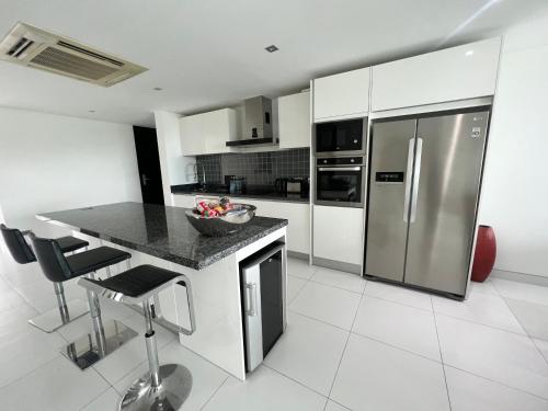 a kitchen with a counter and a stainless steel refrigerator at Twin Sands Resort Penthouse in Patong Beach