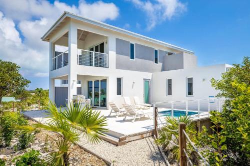a white house with a patio and a swimming pool at NEW Tropical Waterfront Cooper Jack Bay Villas in Five Cays Settlement