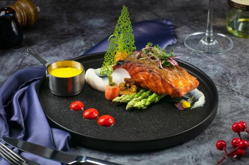 a plate of food with a piece of meat and vegetables at Lucien Hanoi Lakeside Hotel & Rooftop in Hanoi