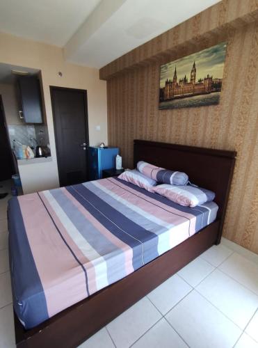 ein Schlafzimmer mit einem großen Bett und einem Gemälde an der Wand in der Unterkunft Apartemen Msquare Cibaduyut 23 m studio in Bandung