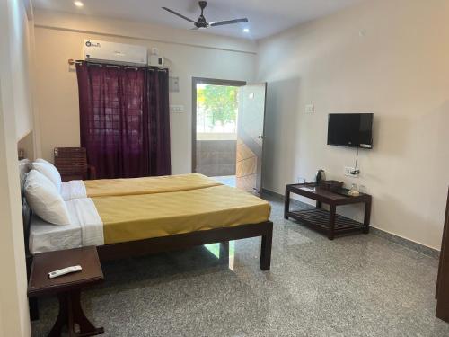 a bedroom with a bed and a television in it at Rt Service Apartments Hotel in Velankanni