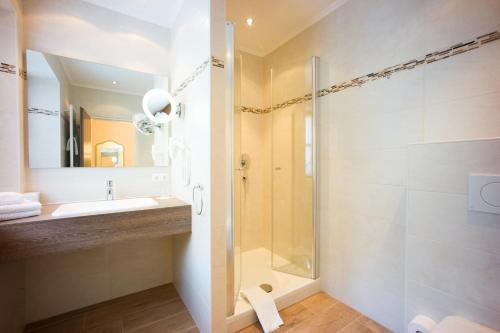 a bathroom with a shower and a sink and a mirror at Hotel Klosterhotel Ludwig der Bayer in Ettal