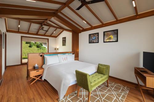 a bedroom with a bed and a chair and a television at Welcomhotel By ITC Hotels, Jim Corbett in Marchula