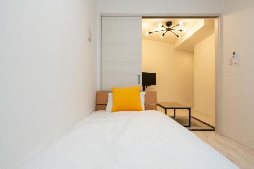 a bedroom with a white bed and a yellow pillow at TASUKI smart Higashishinjuku in Tokyo