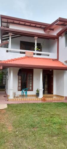 Biały dom z niebieską ławką przed nim w obiekcie Chathu Home Stay w mieście Ambalangoda
