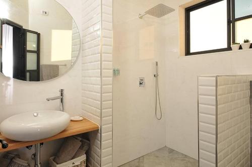 uma casa de banho branca com um lavatório e um chuveiro em סוויטות שלווה עילאית em Sifsufa
