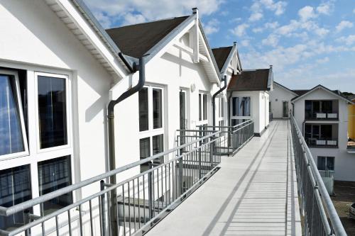 a balcony of white houses with a wooden walkway at Appartementhaus mit Balkon im Ostseebad Göhren HM-01-09 in Göhren