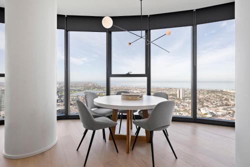 comedor con mesa y sillas frente a las ventanas en Sub Penthouse Southbank Apartment - 3BR, en Melbourne