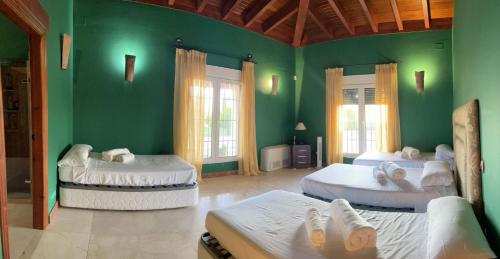 a room with three beds with green walls at finca el descanso manchego in Tarancón