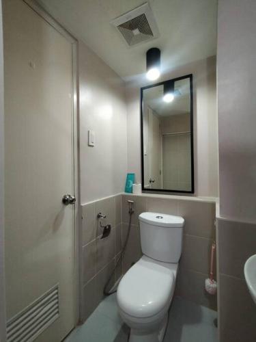 a bathroom with a white toilet and a mirror at Brand New Studio in Pasig with Free Pool Access in Manila