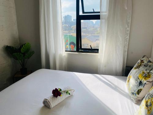 uma cama branca com uma toalha e uma janela em Views from The 509 em Joanesburgo