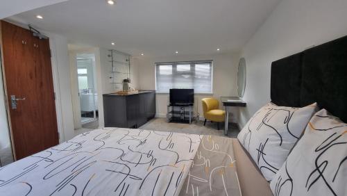 a bedroom with a bed and a desk and a kitchen at Stylish Suites with kitchenette in London Colney