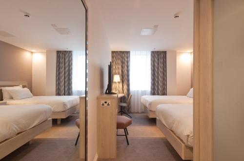 a hotel room with two beds and a mirror at Hampton By Hilton Leeds City Centre in Leeds