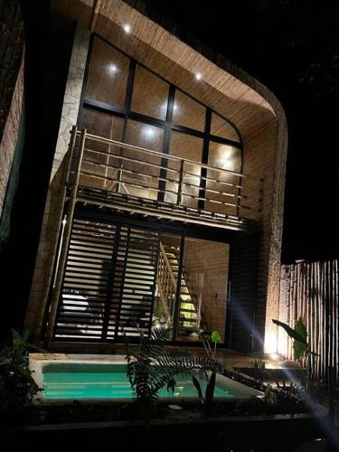 a building with a balcony and a swimming pool at night at Cabaña de Bambú en la Selva in Palenque