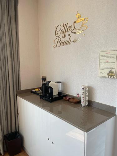 a counter with a coffee maker and a sign on a wall at Nizwa Park House Apartment in Nizwa