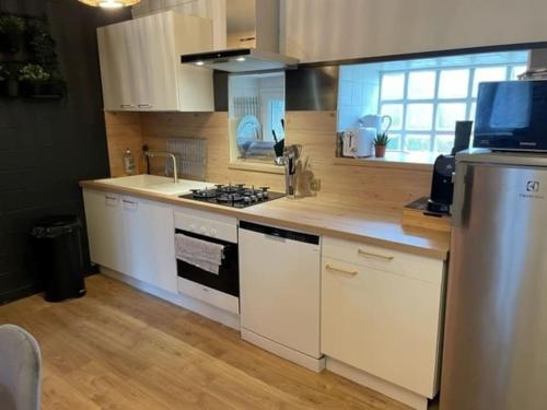 une cuisine avec des armoires blanches et un four à plaques de cuisson dans l'établissement Charmante maison de pecheur dans le Golfe du Morbihan, à Arzon