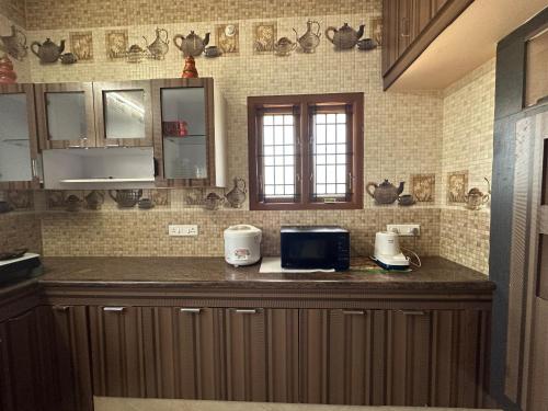 a kitchen with a counter top with a microwave at Jothi Cottage -HomeStay 