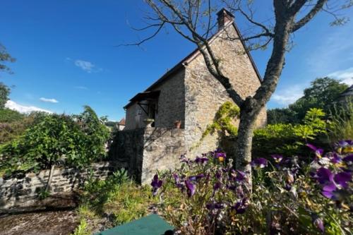 una vieja casa de piedra con flores en primer plano en L'Oustal de l'Olivier, en Rignac