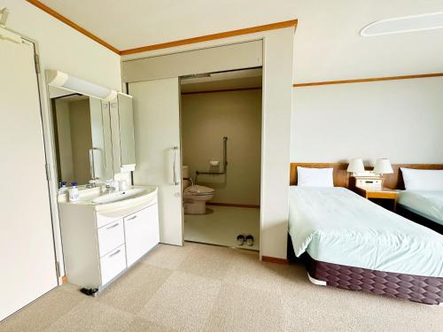 a bedroom with a bed and a bathroom with a sink at 森林公園スイス村 風のがっこう京都 in Kyotango