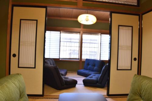a living room with blue chairs and windows at Only for one group Cheaper for 6th & 7th guest 市街地中心部 一棟貸しの宿 in Takayama