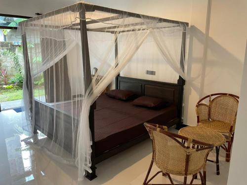 1 dormitorio con cama con dosel, mesa y sillas en ThiliZ Place, en Mirissa