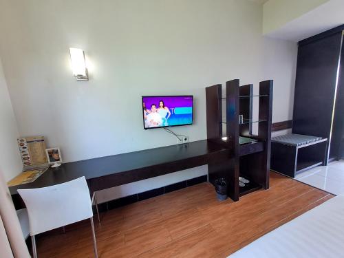HOTEL TILAMAS في Dares: غرفة مع مكتب وتلفزيون على الحائط