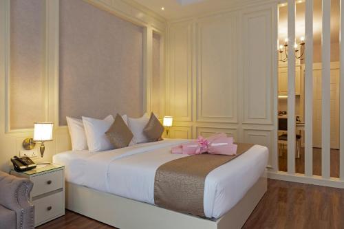 a bedroom with a white bed with a pink bow on it at Anik Boutique Hotel in Phnom Penh