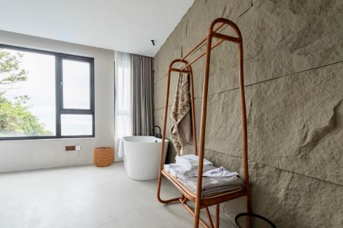 Dengguan Seaview Villa Designer Homestay -Zhoushan Putuo Baisha Island Branch في زهوشان: حمام مع حوض استحمام ساخن بجوار جدار
