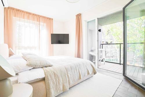 a white bedroom with a bed and a large window at Baltic Pine Retreat W/Balcony, By Cohost in Palanga