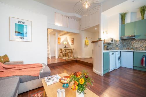 Il dispose d'une cuisine et d'un salon avec un canapé et une table. dans l'établissement Happy Stay Paris - Tournelles Garden, à Paris