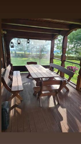 porche de madera con mesa de picnic y bancos en Jiesios sodyba, 