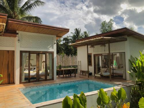 een villa met een zwembad en een huis bij บ้านพราวพร้าว Baan Proud Proud in Khanom