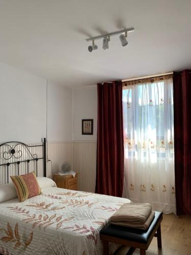 1 dormitorio con 1 cama y una ventana con cortinas rojas en Apartamentos Rurales Corias, en Corias